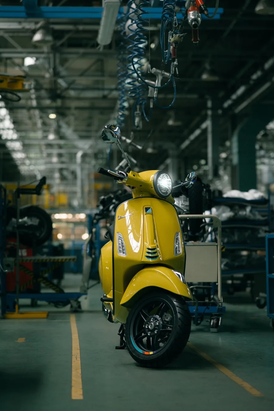Vespa Primavera amarilla en una nave de fábrica, vista de frente